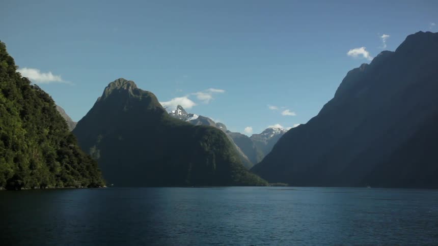 A lake leads to a large mountain range on a sunny day