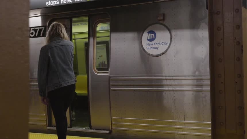 A woman walks over to a train as the door opens