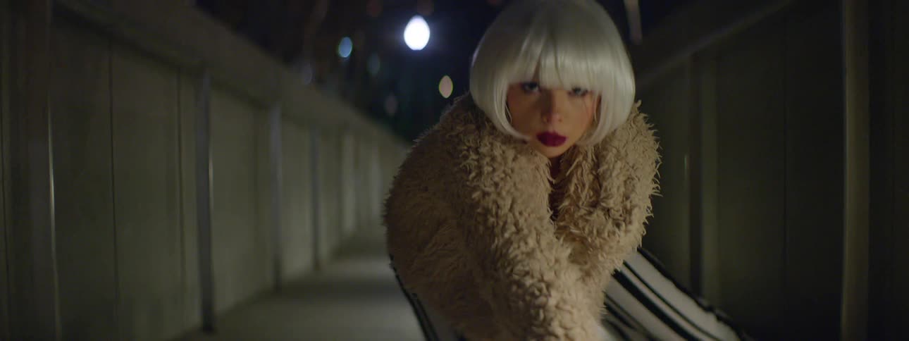 A woman with a fur coat posing on the floor with lights in the background