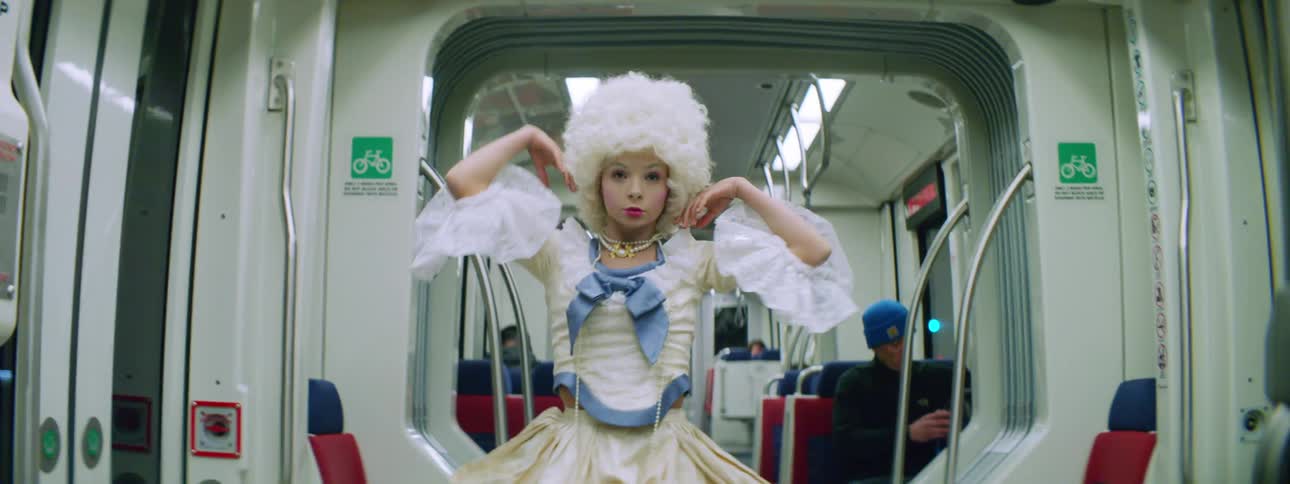 Woman wearing a victorian costume dances inside the car of a train in movement