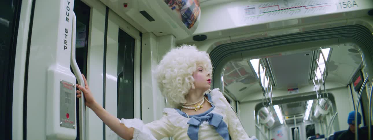 A teenage girl in costume dances on a bus as passengers sit