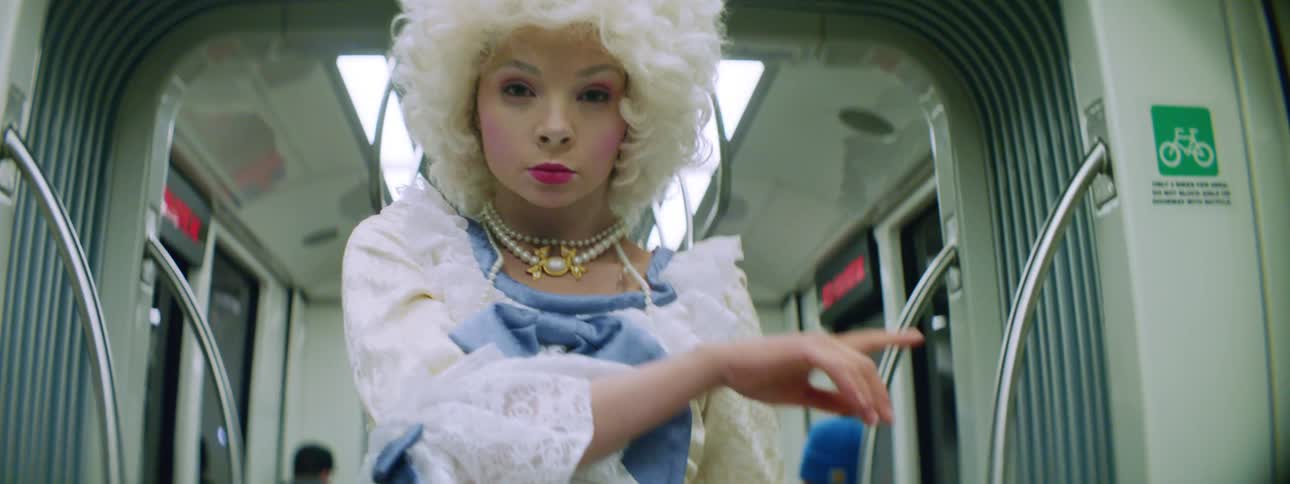 A teenage girl in costume performs on a bus