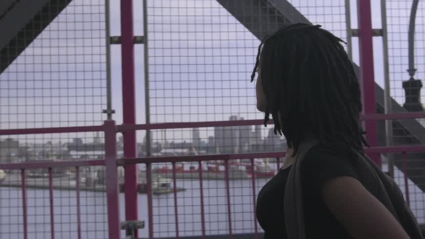 A woman in a black shirt walks near a railing