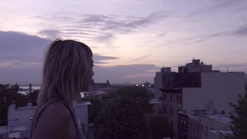 A woman overlooks a town at sunset