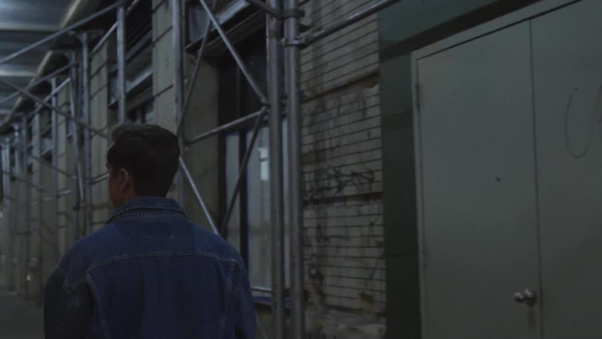 A man is walking outside at night near a building