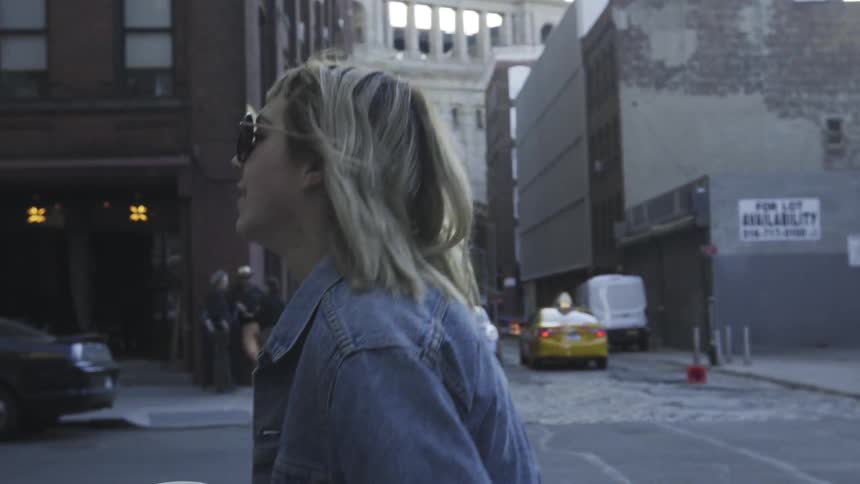 A woman is walking through a city holding a cup