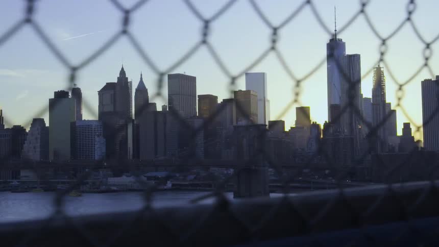 A city beyond a river seen through a chainlink fence