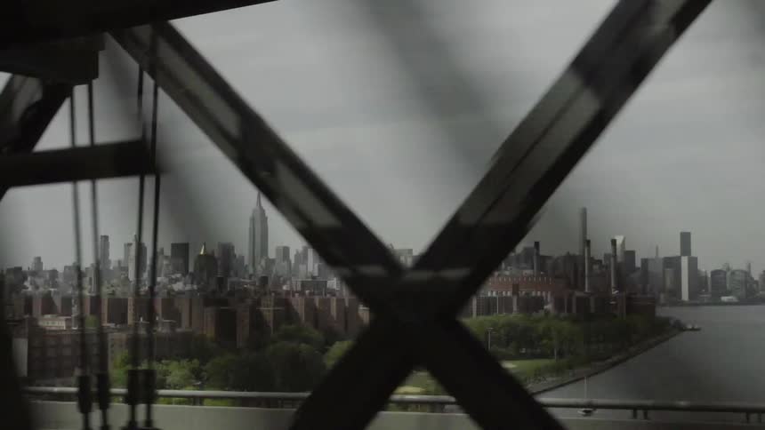 Looking out of a traveling vehicle through a bridge to a city