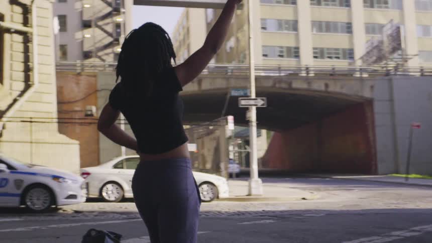 A woman dances on the corner of a city street in the daytime