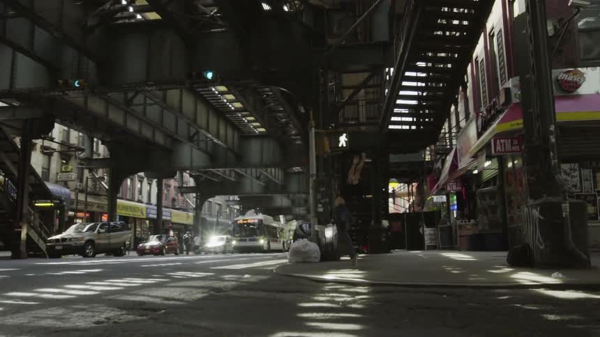 A woman is dancing on the corner under a train station