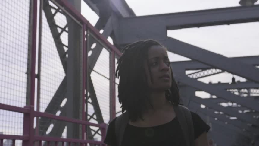 A woman walks over a metal bridge