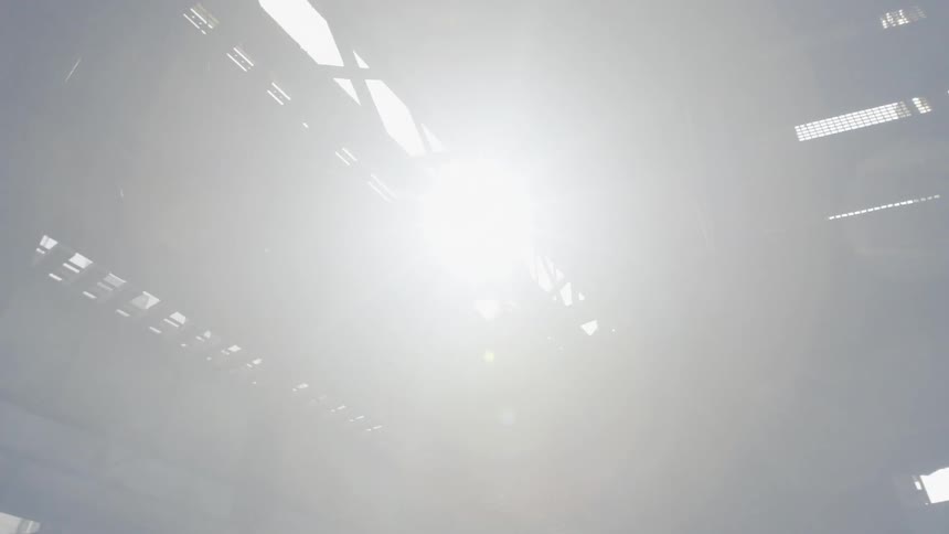The sun is shining through the top of a train platform