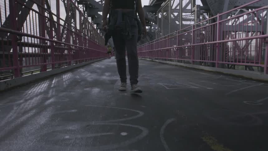 A person walks over a fenced bridge