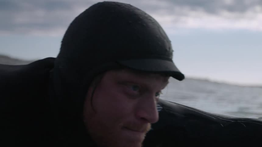 A man is paddling on his surfboard