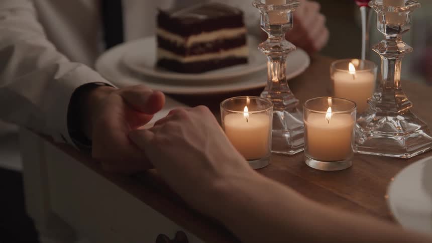 A couple holding hands at a table with dessert