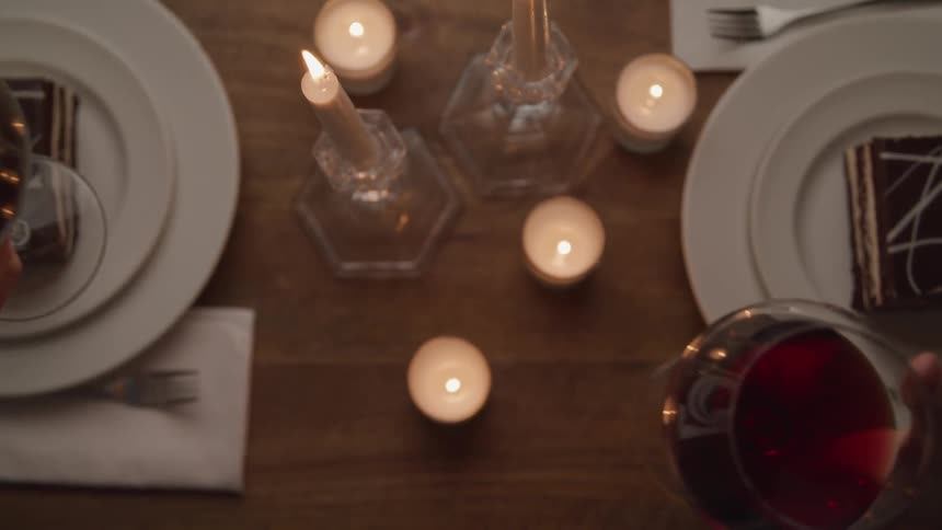Two people celebrate with glasses of red wine at dinnertime