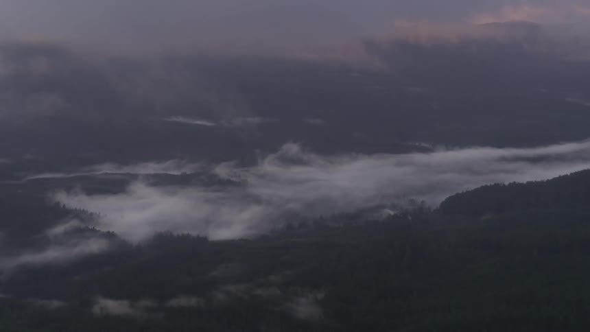 Storm clouds floating over a mountain landscape at sunset