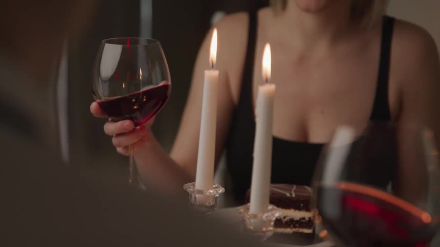 A woman and another person sit at a table at a restaurant with dessert and glasses of wine