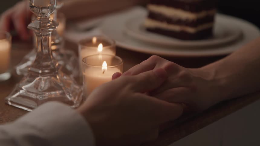 A couple hold hands sitting at a table