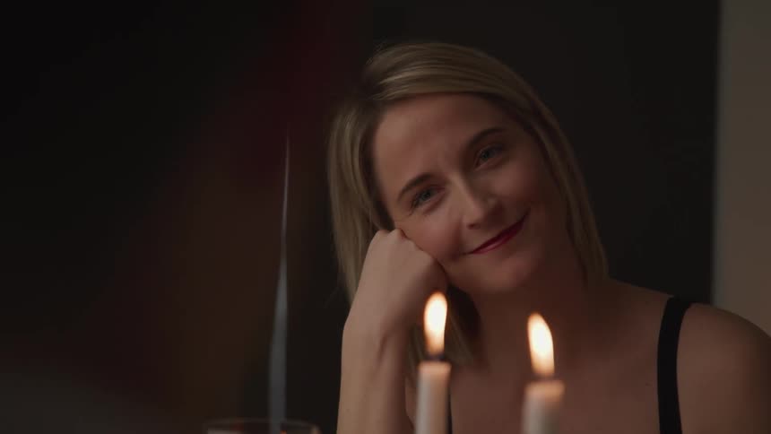 A woman smiles at a man across a candle lit table