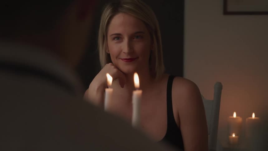 Couple sit across from each other having candlelight dinner