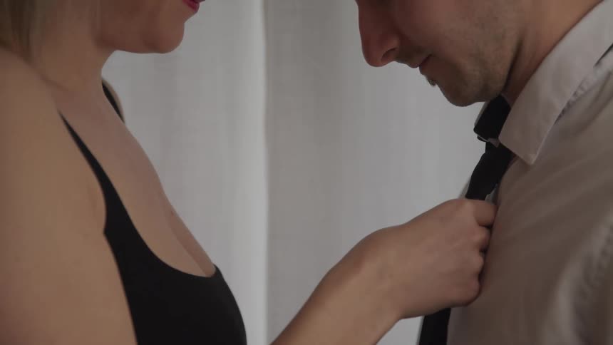 A woman ties a mans tie for him