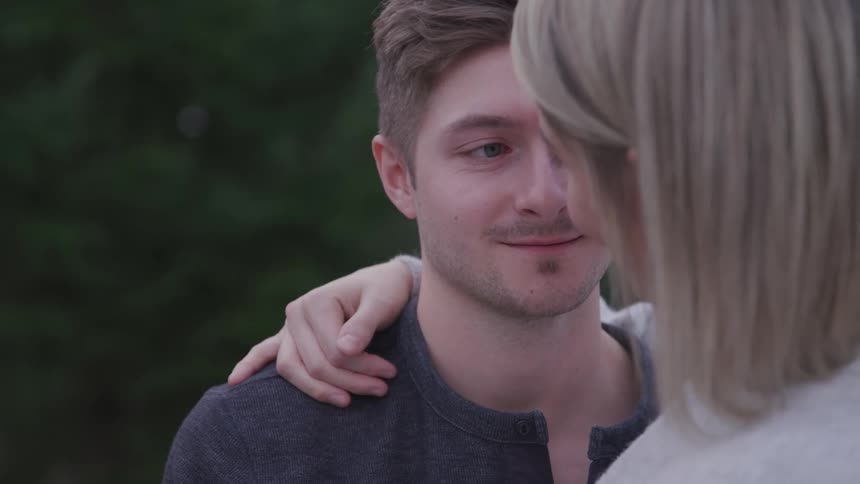 Blonde woman holds her boyfriend and they look into each others eyes