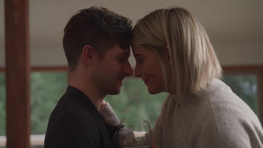 A young couple sitting together indoors an lean towards each other to be nose to nose