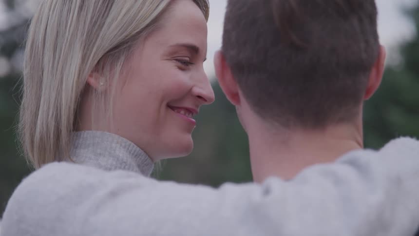 A woman smiles as she embraces a man with one arm