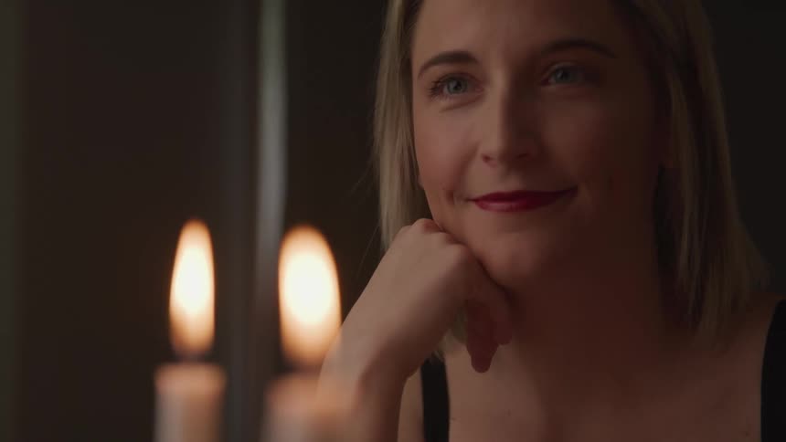 A woman is smiling indoors at night