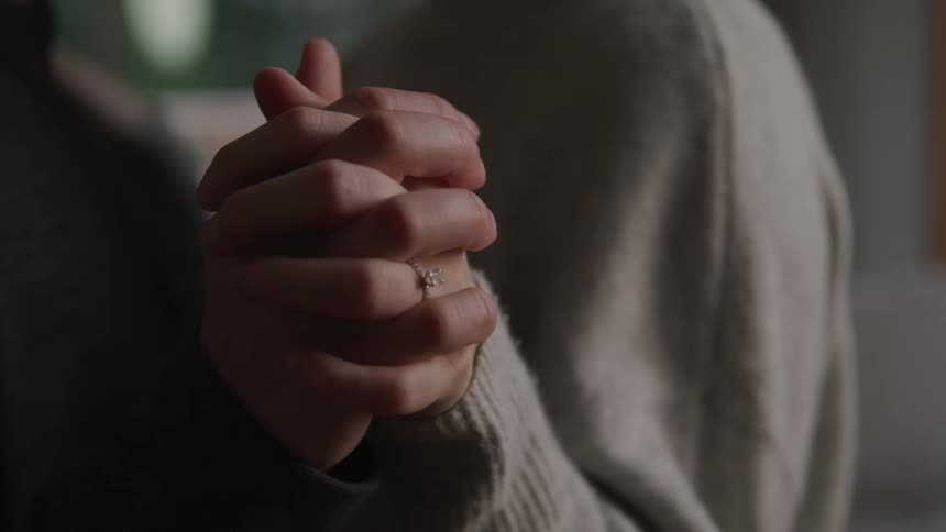 Two people wearing sweaters stand holding hands in dance pose