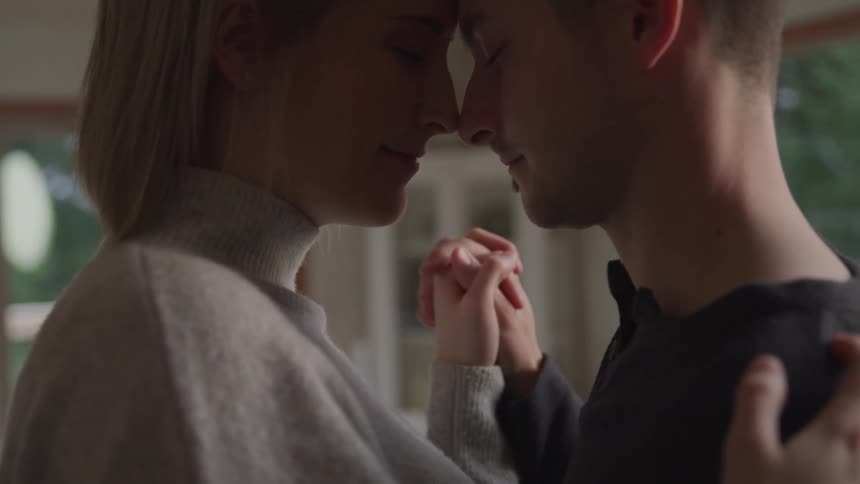 A man and woman dancing closely together inside a home