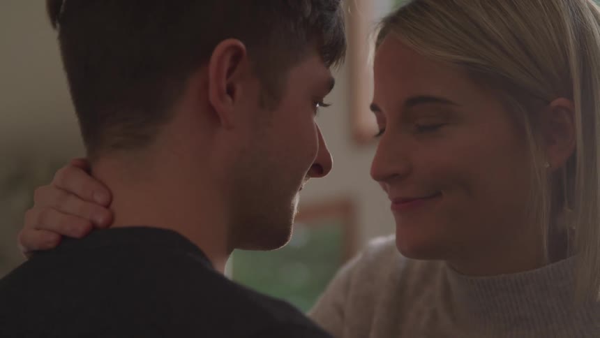 Young couple looking at each other in the eyes before touching foreheads on a room