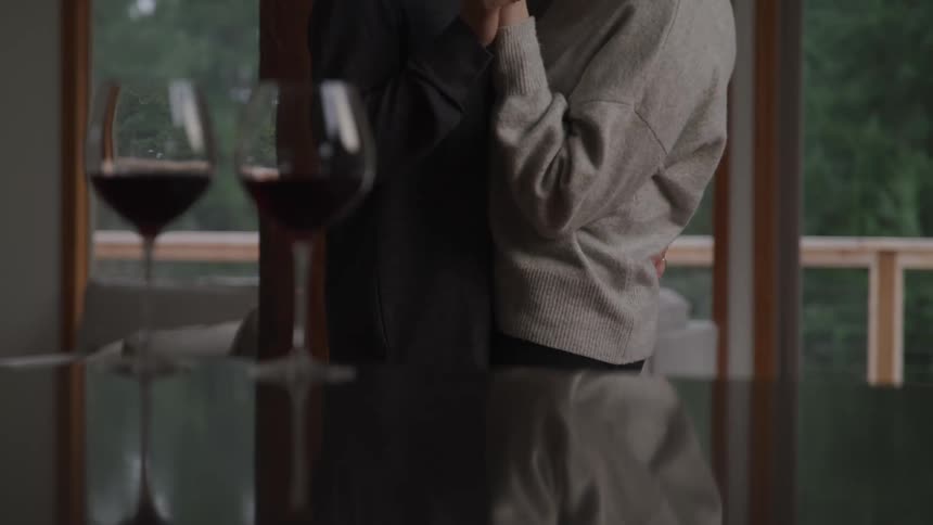 A person pouring wine into glasses on a table