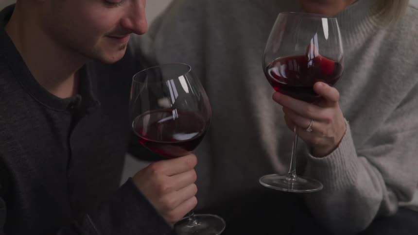 Two people toast and drink wine together