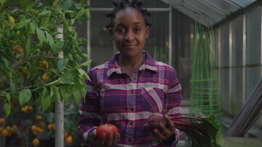 A young girl holding produce in a greenhouse