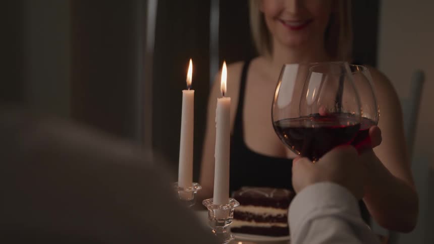A man and woman raise their glasses of wine together as they toast