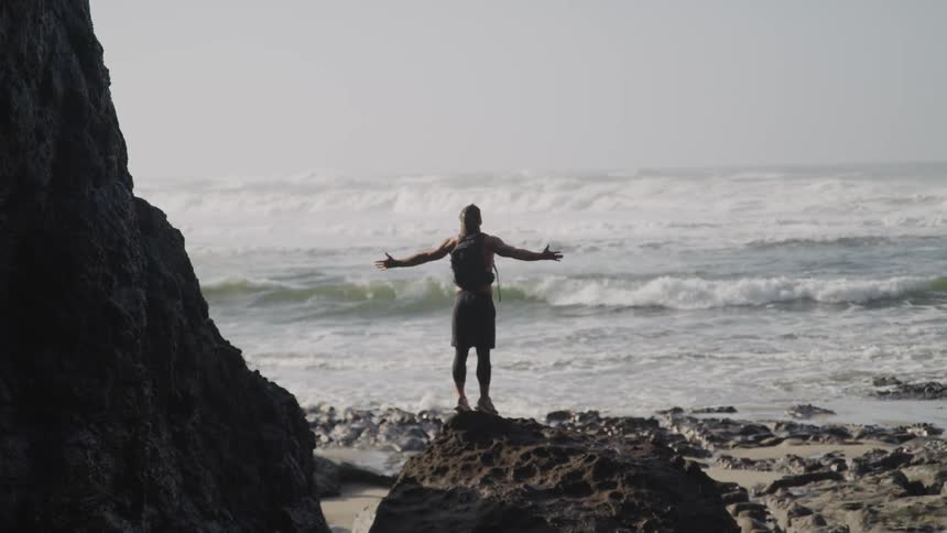 A man stretches his arms out near the water