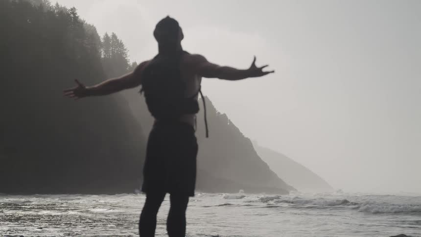 A man stretches his arms out on the beach