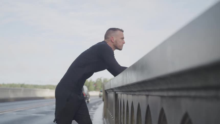 A man is standing outdoors while cars are driving by