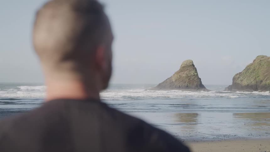 A man is standing outdoors at the beach