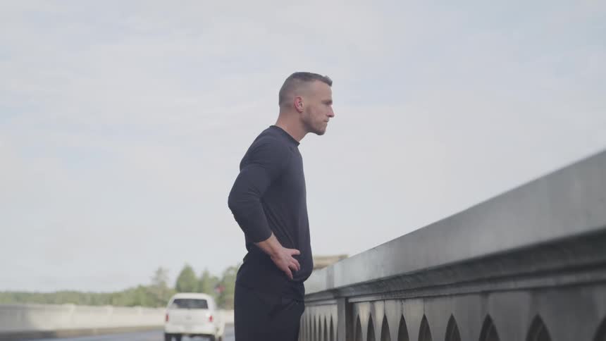A man is standing outdoors while cars are driving by