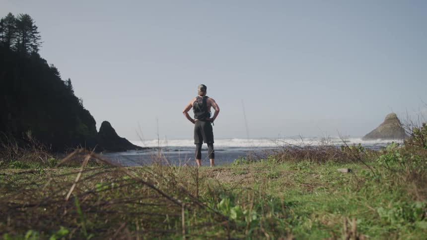 A person standing on the shore looking at the waves rolling in