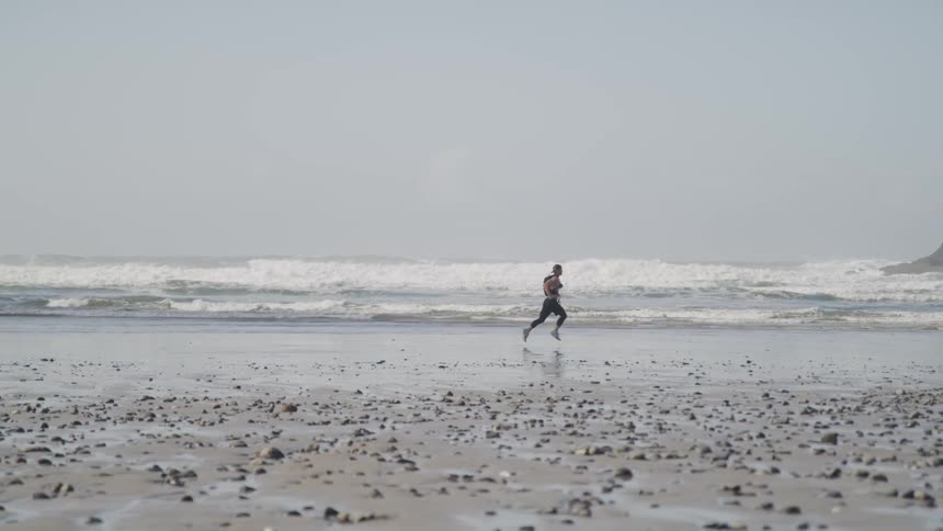A man is jogging outdoors at the beach
