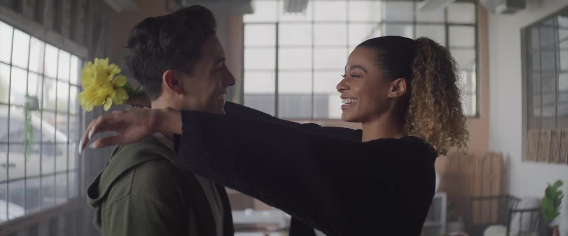 Young man gives her girlfriend a flower and she hugs him smiling