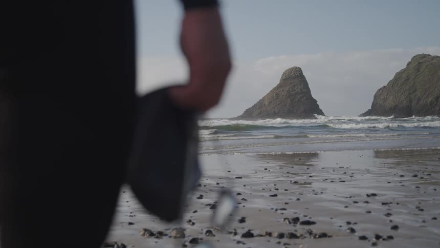 A man stands on the shore and looks out at the waves rolling in