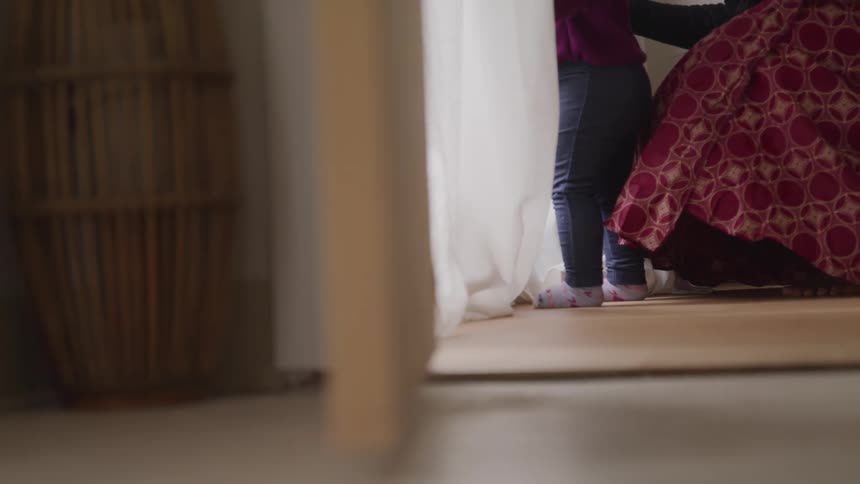 Woman crouches down near toddler looking out window
