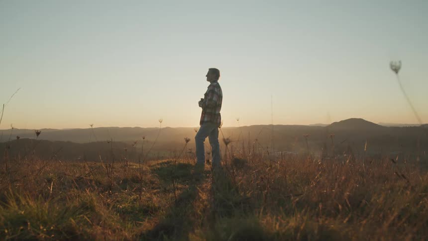 A person is standing outdoors at dusk
