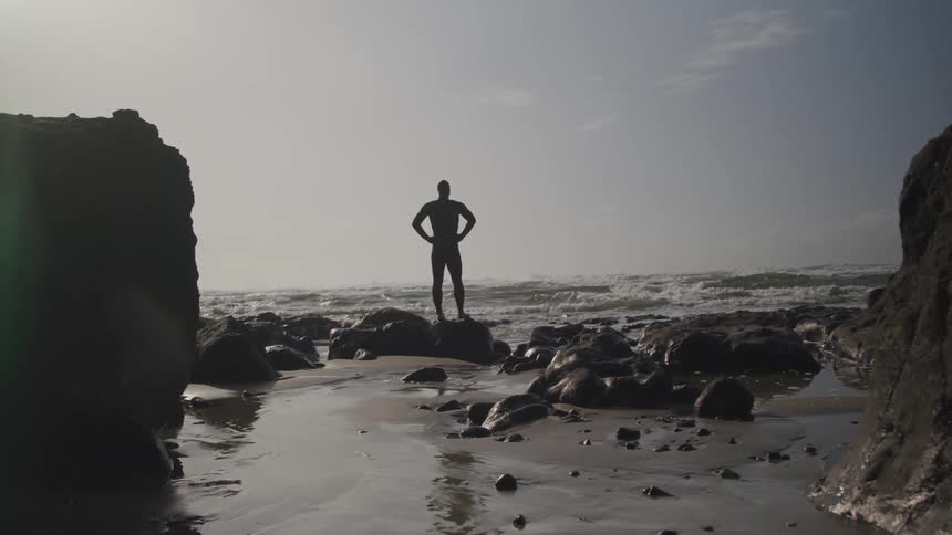 A man is standing by the coast of an ocean