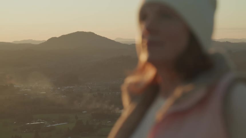 A woman is standing ou tdoors while the sun is setting